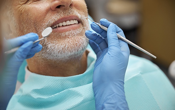 Dentist performing dental checkup and cleaning on male patient