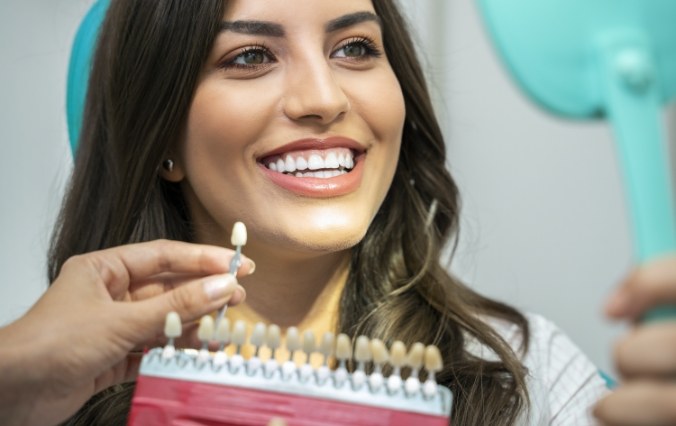 Woman's smile compared to porcelain veneer shade during cosmetic dentistry visit