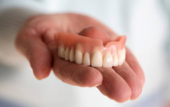 A hand holding dentures in Broken Arrow