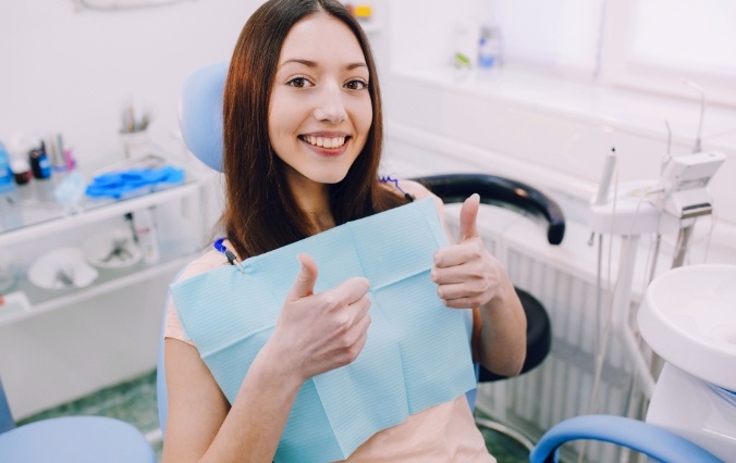 Woman smiling and giving thumbs up after emergency dentistry