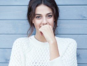 Woman covering her smile after chipped or broken tooth