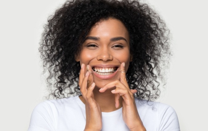 Woman flossing teeth to prevent dental emergencies