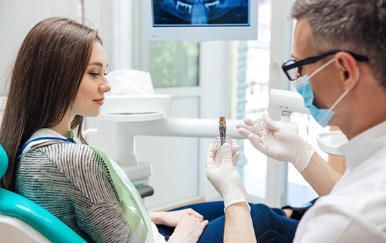 A dentist showing his patient some dental implants