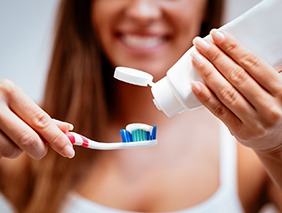 Woman putting toothpaste on a toothbrush