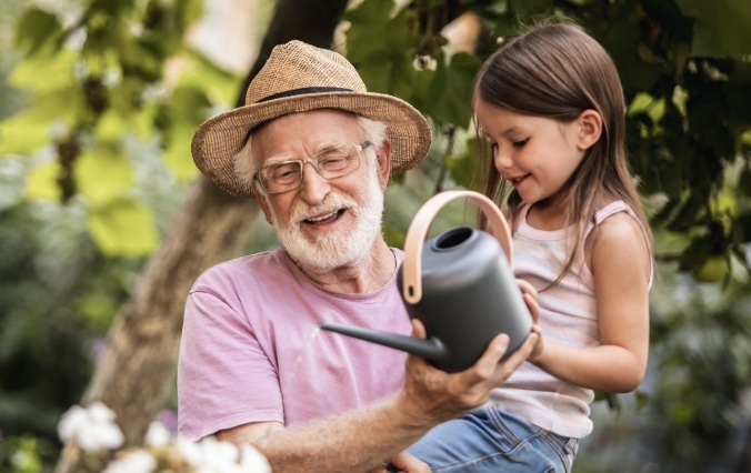 Older man smiling with grandchild after dental implant tooth repalcement