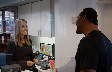 Dental team member greeting patient at reception desk in Broken Arrow