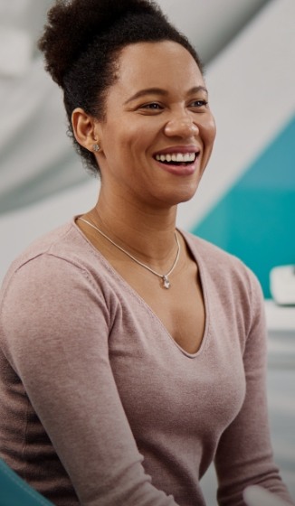 Woman in pink shirt smiling in dental chair