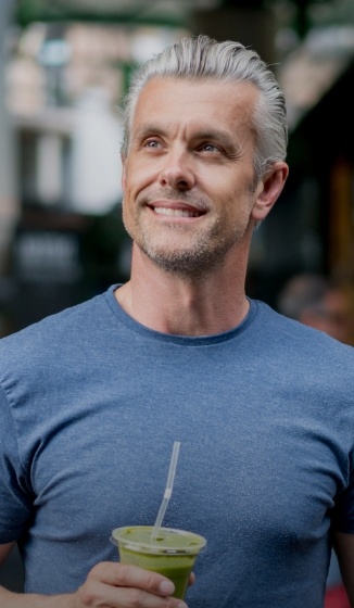 Man in blue shirt holding a beverage with a straw