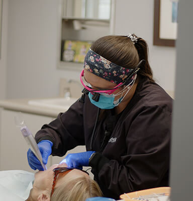 Dental team member examining a patient's mouth in Broken Arrow
