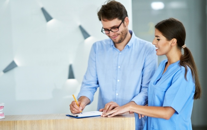 Dental team member and patient looking at dental insurance forms