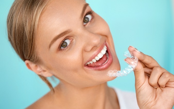 Smiling woman placing an Invisalign tray