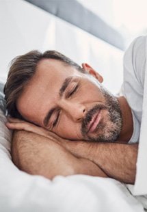 a man resting in bed after sleep apnea treatment