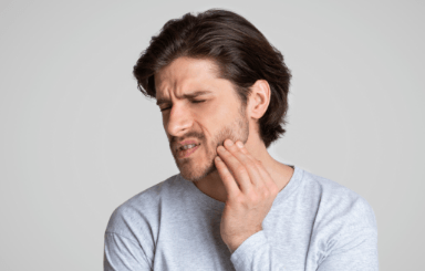 man holding cheek in pain