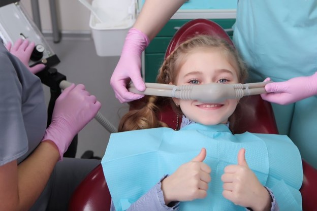 Young girl receiving sedation dentistry and giving thumbs up.