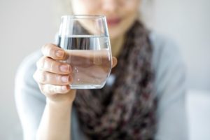 woman holding water and knowing what to eat and drink after All-on-4 surgery