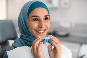 Woman in dental chair about to put in Invisalign® aligner