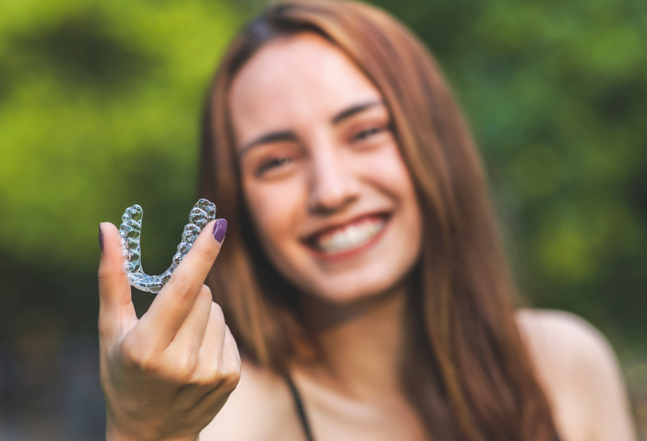 Smiling woman holding clear aligner
